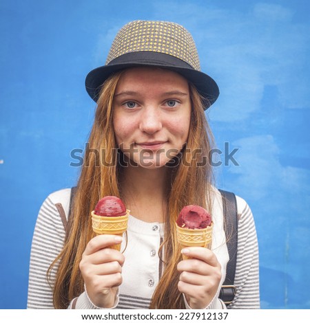 Portrait of nice teen girl with ice cream, blue wall background (Instagram style series)