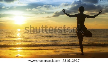 Silhouette young woman practicing yoga on the beach at amazing sunset Silhouette young woman practicing yoga on the beach at amazing sunset