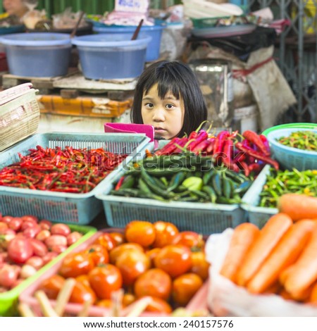 BANGKOK, THAILAND - DEC 15, 2014: Unidentified girl child seller on the Burmese street market in Bangkok. There is 16,000 registered street vendors in Bangkok.