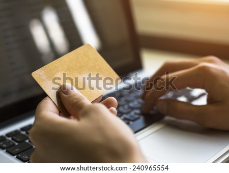 Card (with place for your text) in hand and entering security code using laptop keyboard.