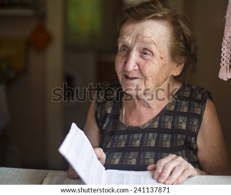 Old woman emotionally talks and reads in a notebook in his house.
