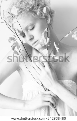 Closeup beautiful thin with curly hair girl model with a dry tree branch, black and white photography.
