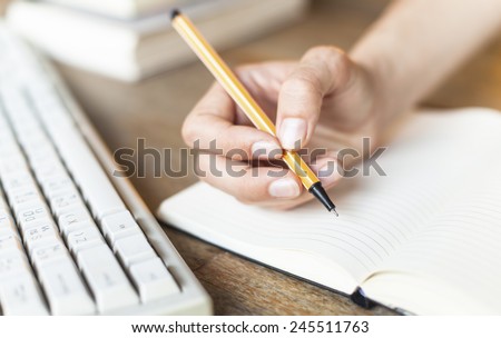 Handwriting, female hand writes with a pen in a diary notebook.