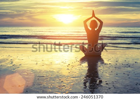 Silhouette of yoga woman meditating on the ocean beach. Fitness. Healthy lifestyle.