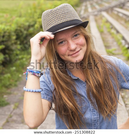 Cute teen girl wearing a hat, outdoors in the park (square series)