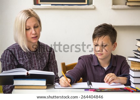 Young student learns at home with a his mom tutor.