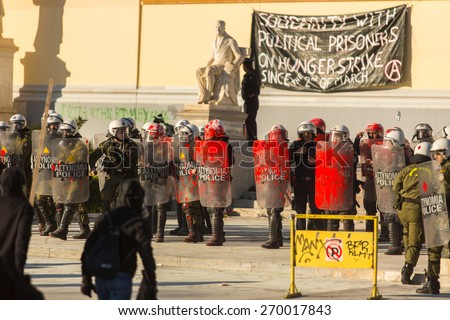ATHENS, GREECE - APR 16, 2015: Riot police with their shield, take cover during a rally in front of the Athens University, which is under occupation by protesters leftist and anarchist groups.