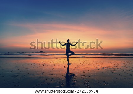 Yoga silhouette. Woman doing meditation near the ocean.