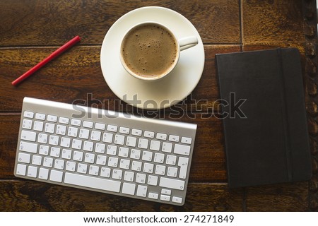 Keyboard, black notebook with pencil and a Cup of coffee, top view of the texture of an old tree.