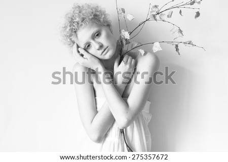 Young tender girl with a dry branch in his hand. Black and white photography in bright colors.