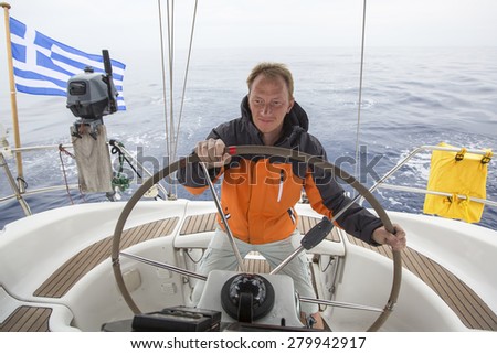 Young skipper drives the sailboat in the open sea. Yachting. Sailing.