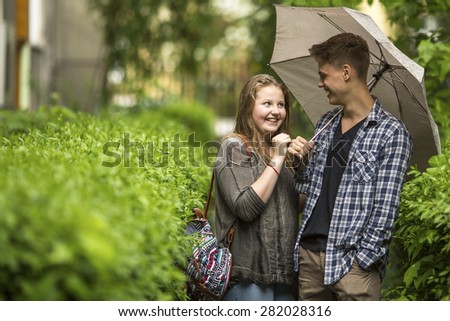 Boy and girl having fun in the Park under an umbrella.