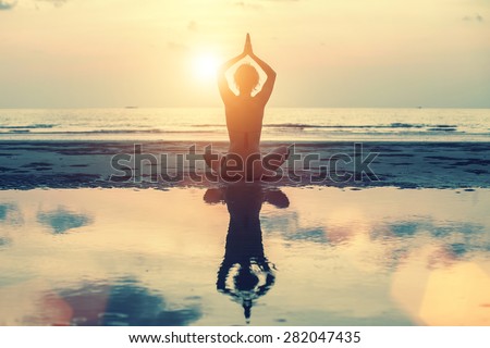 Meditation, yoga and fitness, a healthy lifestyle. Silhouette of a beautiful yoga woman at sunset in surreal colors.