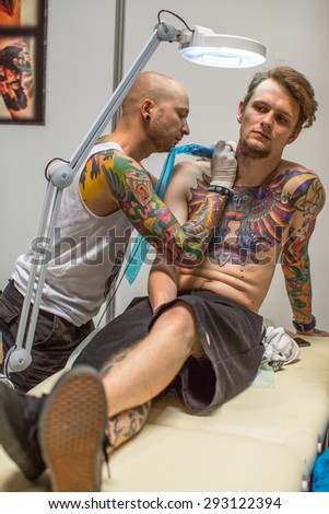 KRAKOW, POLAND - JUNE 6, 2015: People make a tattoos at the 10-th International Tattoo Convention in the Congress-EXPO Center. This year anniversary TattooFest is tattoo Studio with an area of 2000m2.