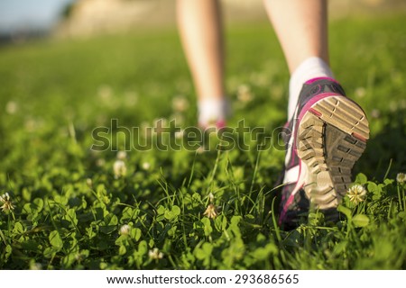 Hiker walking in the green grass outdoors, low angle close up of the foot.
