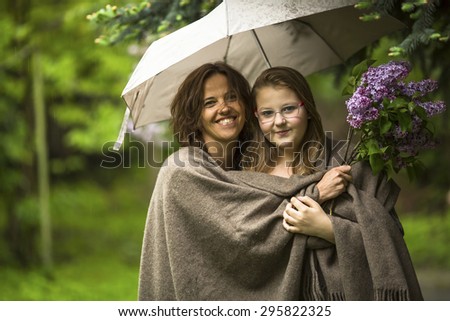 Woman with her daughter under an umbrella in the Park in the rain.