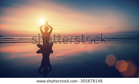 Silhouette meditation girl on the background of the sea and sunset. Yoga and healthy lifestyle.