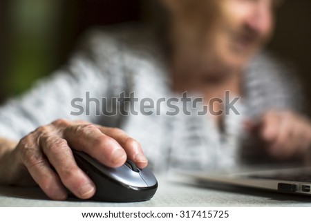 Closeup of the hand of an old woman holding a computer mouse.