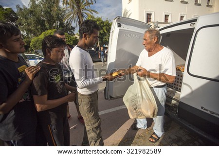 KOS, GREECE - SEP 27, 2015: War refugees receive humanitarian assistance - bread. More than half are migrants from Syria, but there are refugees from other countries-Afghanistan, Pakistan, Iraq, Iran.