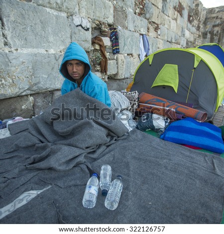 KOS, GREECE - SEP 28, 2015: Unidentified war refugee near tents. More than half are migrants from Syria, but there are refugees from other countries -Afghanistan, Pakistan, Iraq, Iran, Mali, Somalia.