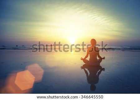 Silhouette meditation yoga woman on the background of the sea and amazing sunset. Healthy lifestyle.