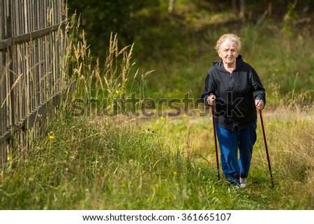 An elderly woman practices Nordic walking in the Park.