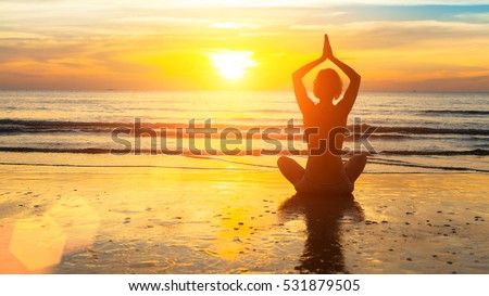 Silhouette woman yoga on the sea beach at sunset.