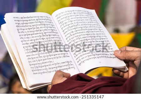 BODHI GAYA, INDIA - January 27, 2015.: Tibetan monk are celebrating a ceremony beneath the bodhi tree, under which the buddha became enlightened. He\'s chanting and reading from his book.