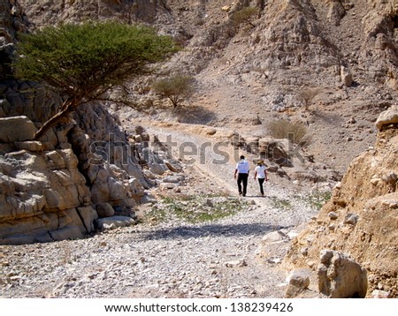 Two people walking along a rocky trail in Ras al Khaimah.