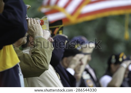 Veterans Salute the US Flag during  Memorial Day service.