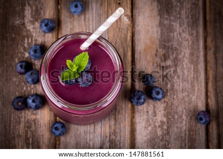 Blueberry Smoothie In A Glass Jar With A Straw And Sprig Of Mint, Over Vintage Wood Table With Fresh Berries.