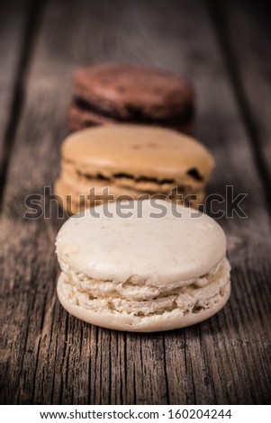 Assorted macaroons over old wood background. Vintage effect processing with intentional vignetting