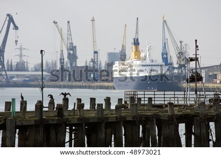 The derelict old pier at Southampton docks with cruise ship, dockside and cranes behind.