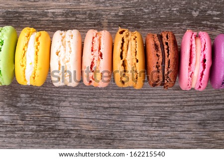 Assortment of French macaroons in rainbow colours, over old wood background with space for your text.