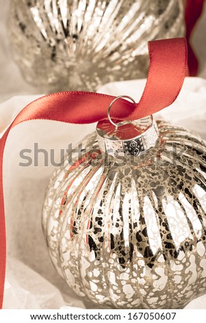 Antique glass Christmas tree baubles wrapped in protective tissue, and threaded on to a red satin ribbon.