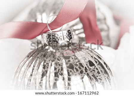 Antique glass Christmas tree baubles wrapped in tissue, and threaded on to a red satin ribbon.