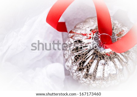 antique glass Christmas tree baubles wrapped in protective tissue, and threaded on to a red satin ribbon. Space for your text