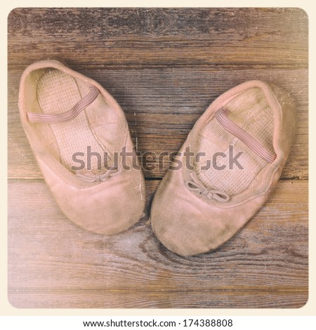 A pair of tiny ballet shoes on old wood floor, with nostalgic feel suitable for mother\'s day or grandparents day. Filtered to look like an aged instant photo.