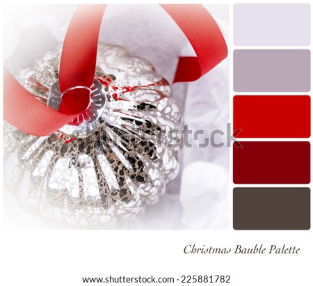 An antique glass Christmas tree decoration, on a red ribbon, and nestled in tissue paper wrapping. In a colour palette with complimentary colour swatches.