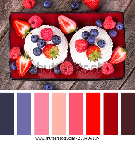 A platter of summer fruits in meringue nests, over old wood background, with a palette of complimentary colour swatches.