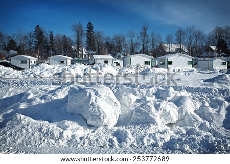 Fishing huts in the snow at Ste-Anne De La Perade in Quebec province, Canada. A village of small huts are assembled on the frozen river each year for the ice fishing season.
