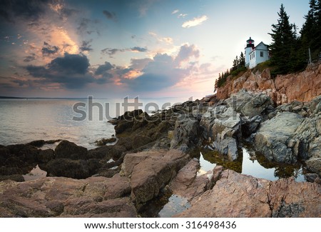 Sunset at Bass Harbor Lighthouse, with the light reflected ed in the rock pools, Mount Desert Island, Maine, USA