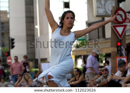 AURILLAC, FRANCE - AUGUST 22: a young woman dances in the street as part of the Aurillac International Street Theater Festival,show by the Company Rebus ,on august 22, 2012, in Aurillac,France.