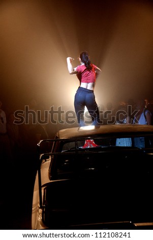AURILLAC, FRANCE - AUGUST 22: a woman dances and sings on the bonnet of a car under a big top, Aurillac International Street Theater Festival, Company Off ,on august 22, 2012, in Aurillac,France.