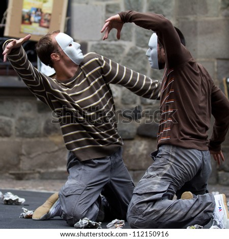 AURILLAC, FRANCE - AUGUST 24: two masked dancers are kneeling, face to face, as part of the Aurillac International Street Theater Festival, Company Idem,on august 24, 2012, in Aurillac,France.