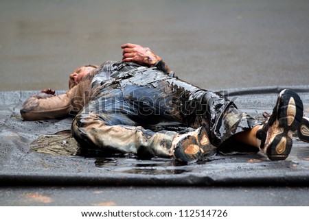 AURILLAC, FRANCE - AUGUST 22: a very dirty and lifeless body in the street as part of the Aurillac International Street Theater Festival, show named Vachement, on august 22, 2012, in Aurillac,France.