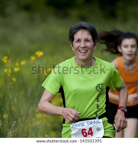 PAVIE, FRANCE - JUNE 23: Elderly runner at the Trail of Pavie, on June 23, 2013, in Pavie, France.  She is smiling, Behind her, we can see a very young competitor.