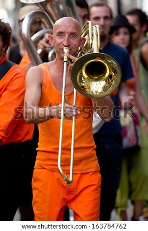AURILLAC, FRANCE - AUGUST 21:An unidentified musician walks and plays the trombone in the street, as part of the Aurillac International Street Theater Festival, on august 21,2013, in Aurillac,France.