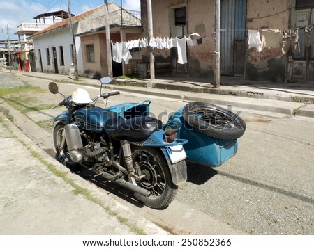 BARRACOA, CUBA - NOVEMBER 24: a vintage blue side-car is parked in a street and some clothes are hung out to dry on the other side,on november 24, 2014, in Vinales, Cuba.