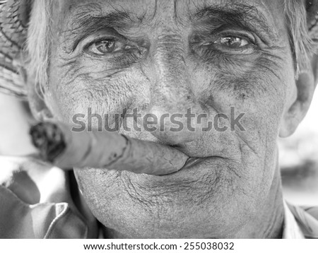 VINALES, CUBA - DECEMBER 16: portrait of an old man wearing a straw hat and smoking a cuban cigar outdoors,on december 16, 2014, in Vinales, Cuba